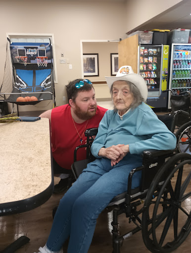A heartwarming moment shared between a man and an elderly woman in a care facility.