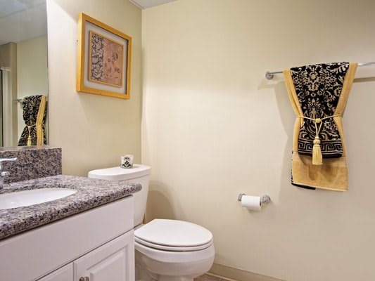 A clean and modern bathroom with a toilet, sink, and decorative towels.