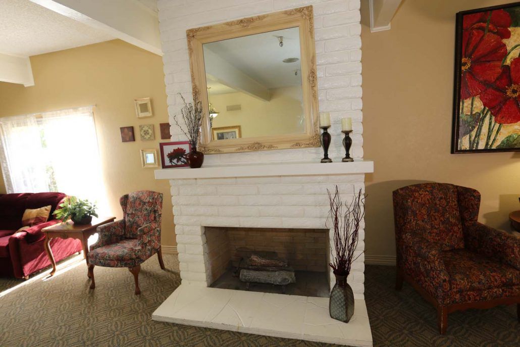 A cozy living room featuring a white brick fireplace with a large mirror above it.