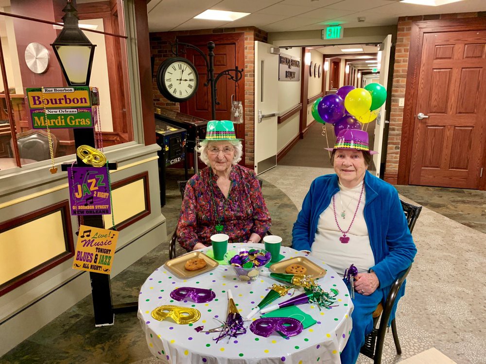 Two people enjoying a festive Mardi Gras celebration with colorful hats and decorations.