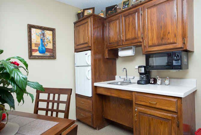 A cozy kitchen corner featuring wooden cabinets, a refrigerator, sink, and countertop appliances such as a microwave and coffee maker.