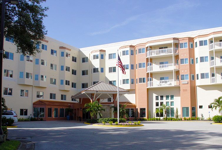 A multi-story residential building with a central entrance and an American flag in front.