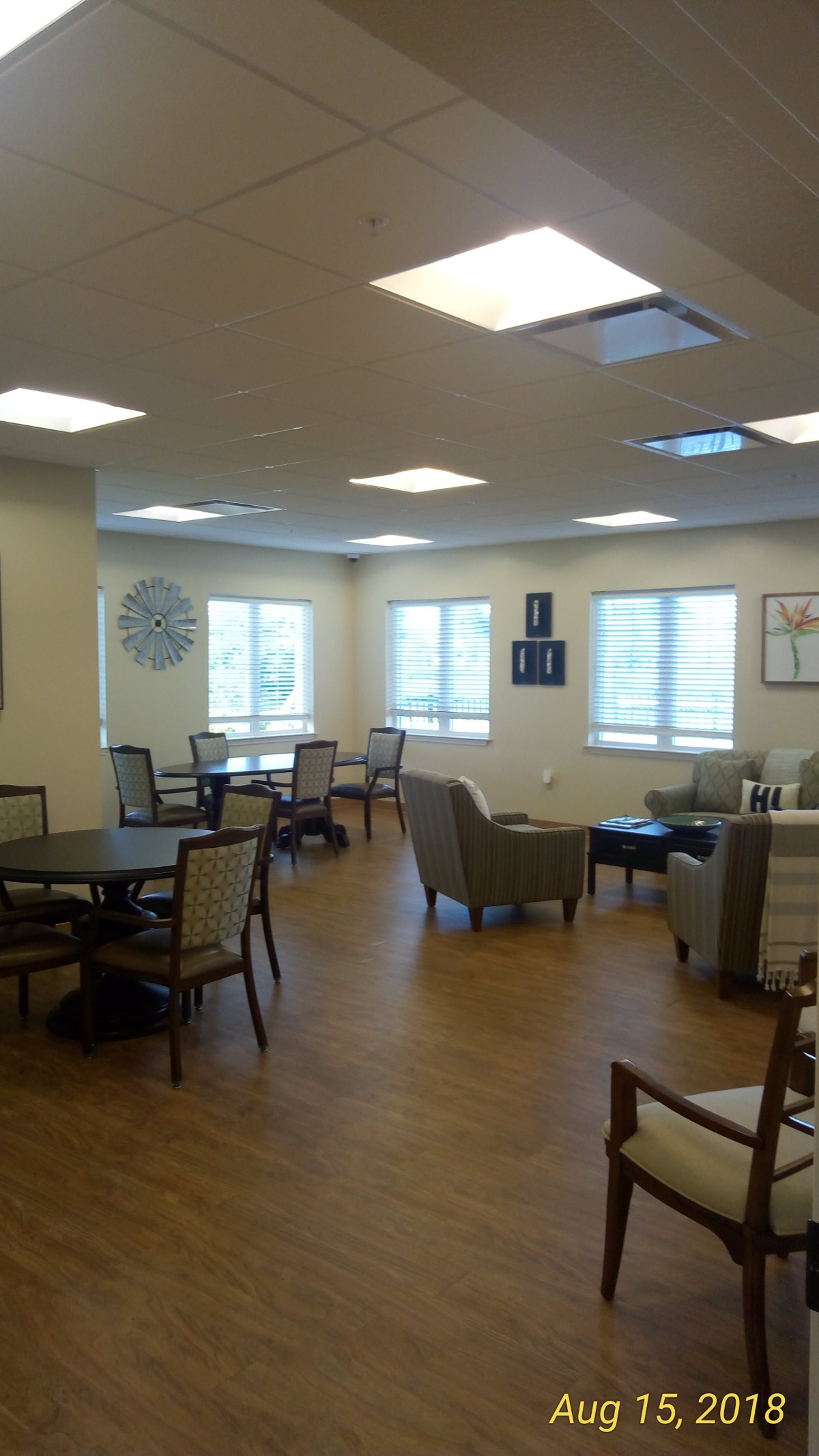 A cozy seating area with tables and chairs, well-lit by natural light from several windows.