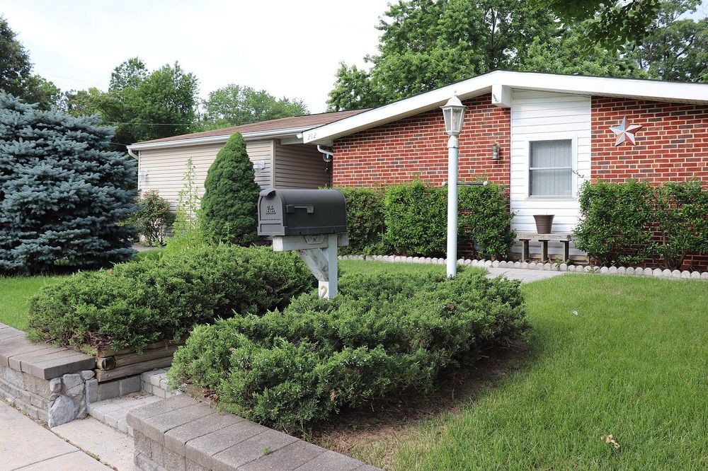 A suburban house with a well-maintained yard featuring bushes and a mailbox.