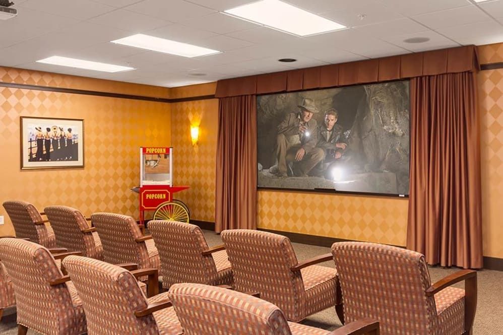 A cozy home theater room equipped with comfortable seating, a large projector screen, and a classic popcorn machine.