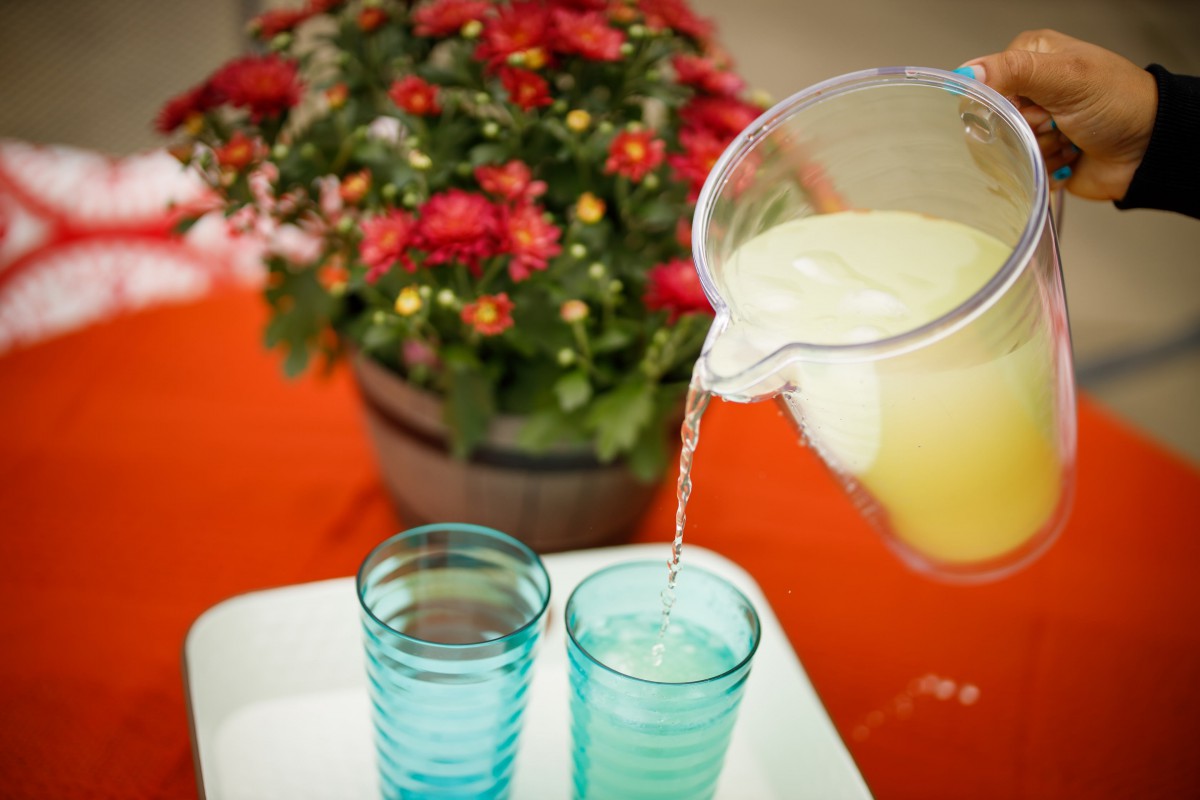 Refreshing lemonade being poured into glasses with flowers in the background.