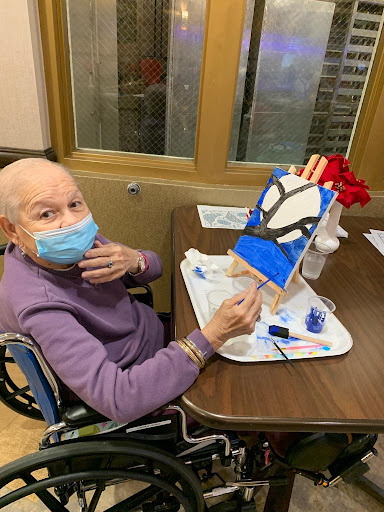 An elderly individual creatively engages in painting while seated in a wheelchair, showcasing their artistic skills.