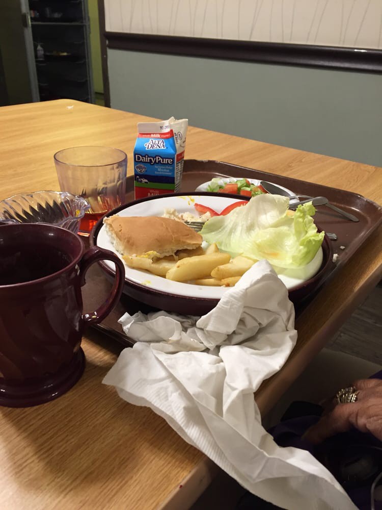 A tray with a sandwich, fries, lettuce, and drinks on a table.