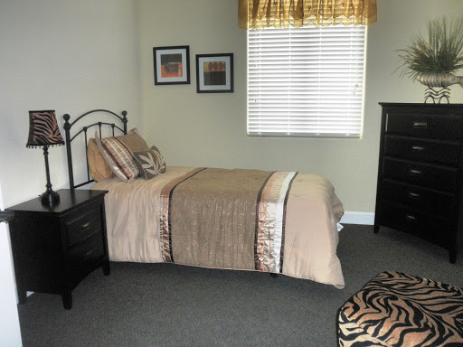 A cozy, well-lit bedroom featuring a neatly made bed, stylish furniture, and decorative accents.