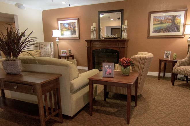 A cozy living room featuring a fireplace, sofa, and coffee table, adorned with art and decor.