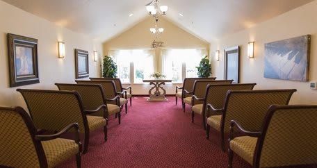 A serene chapel interior with rows of chairs and natural light streaming through large windows.