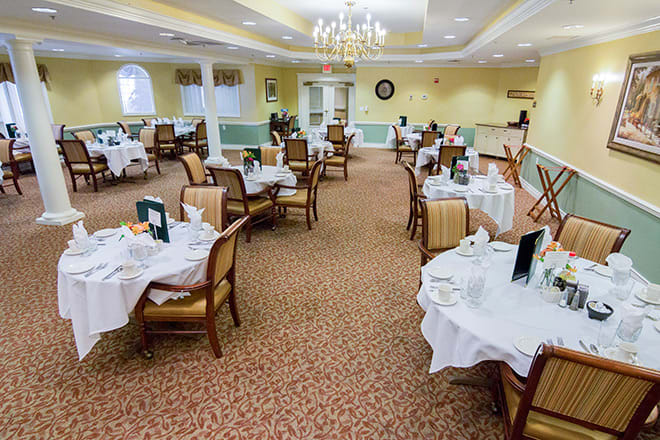 An elegant dining room with neatly arranged tables and chairs, set for a meal.