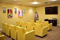 A cozy home theater room featuring rows of bright yellow chairs and vibrant wall art.