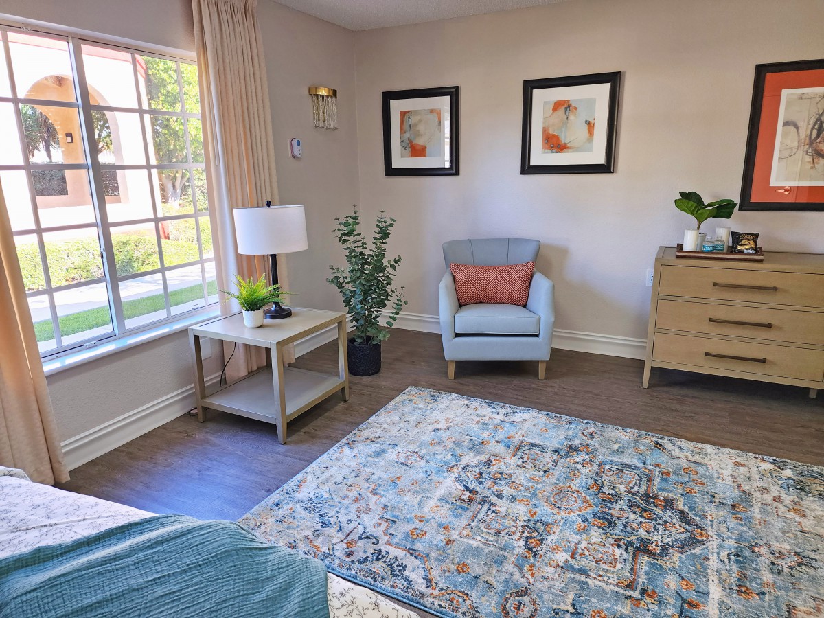 A cozy living room with an armchair, decorative plants, and framed artwork on the walls.