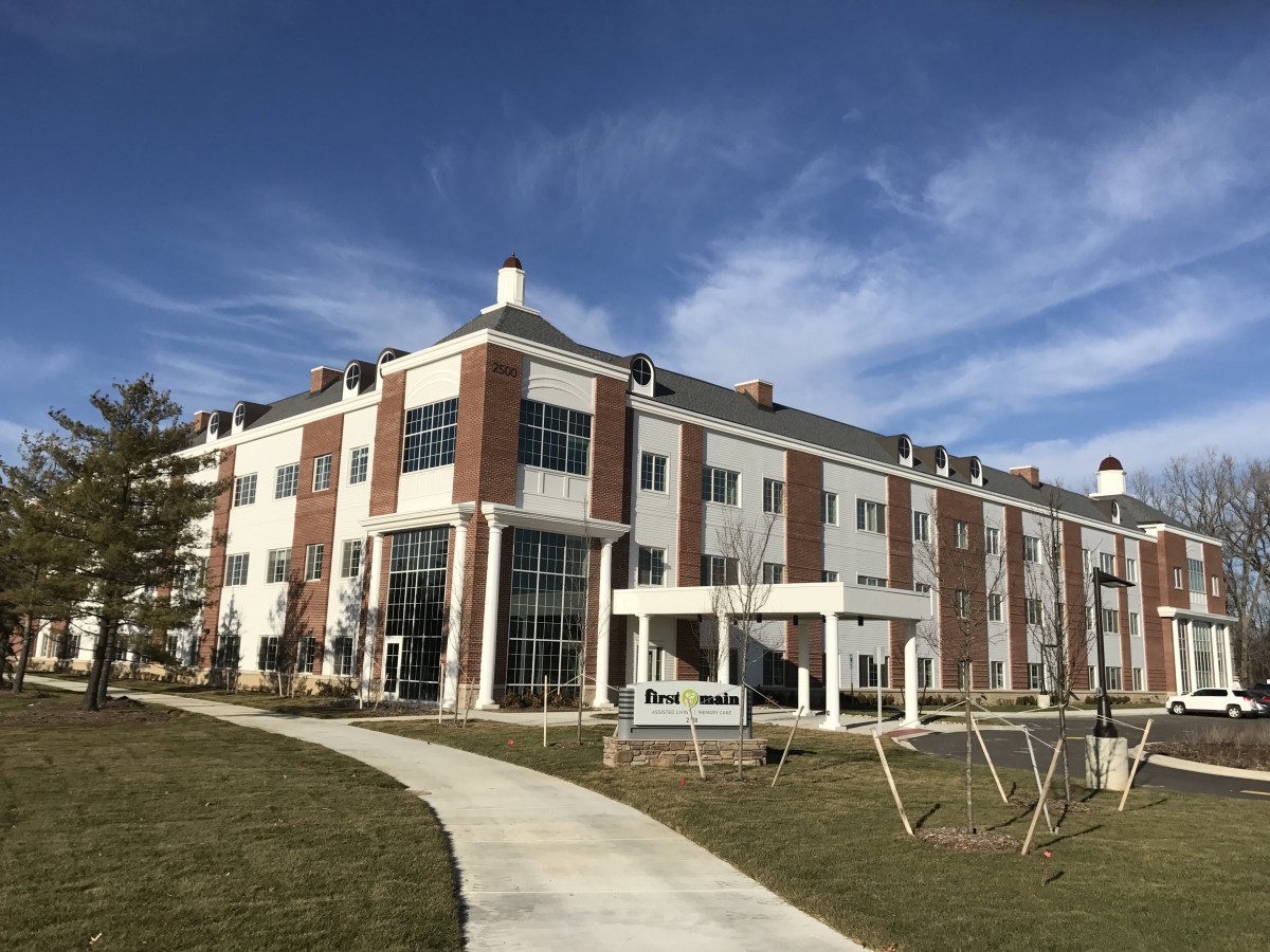 A modern multi-story building with brick and white facade under a clear blue sky.