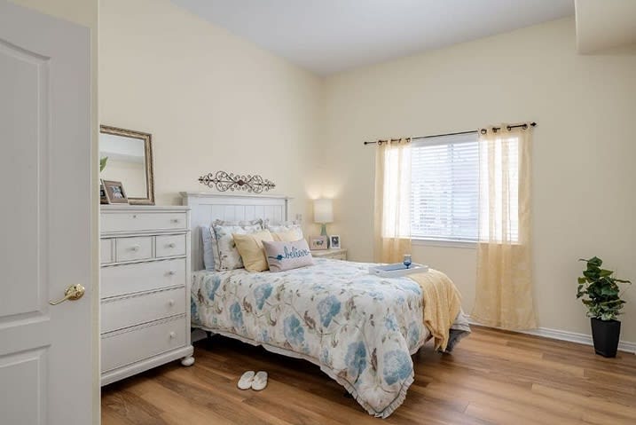 A cozy bedroom with a neatly made bed and a window allowing natural light.