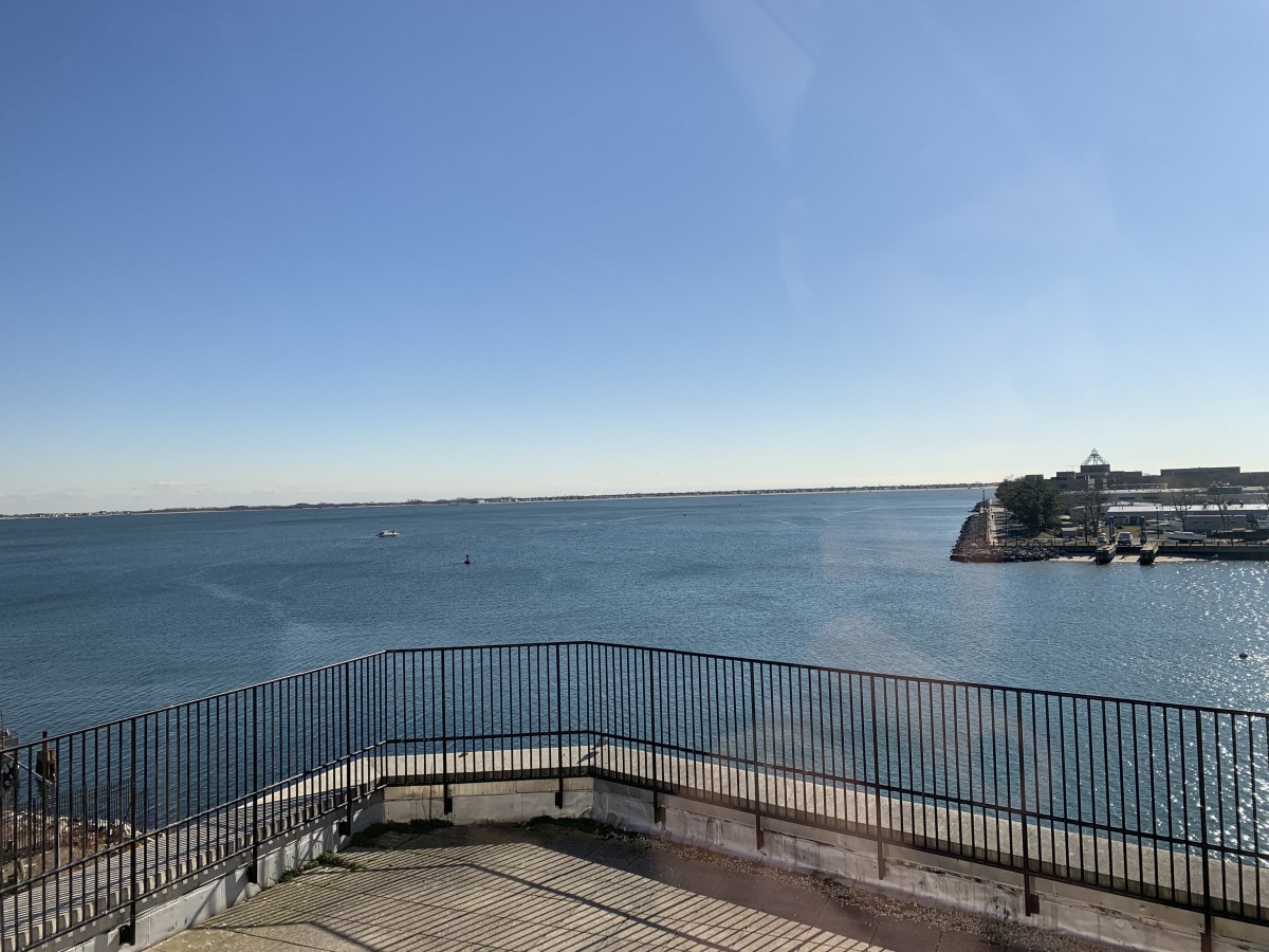 A clear view of the ocean with blue skies and a coastal railing.