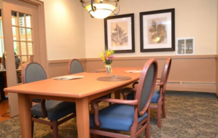 A meeting room with a wooden conference table, surrounded by chairs, adorned with wall art and a central lighting fixture.