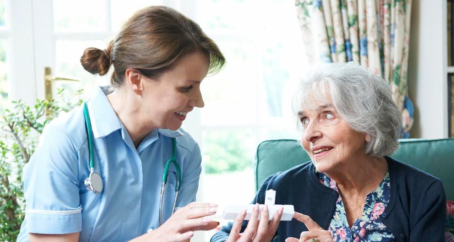 A nurse assisting an elderly woman with her medication in a home setting.