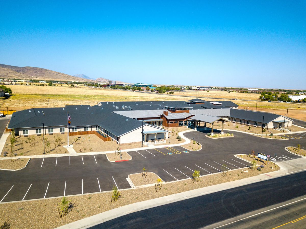Aerial view of a modern building with a spacious parking lot and surrounding landscape.