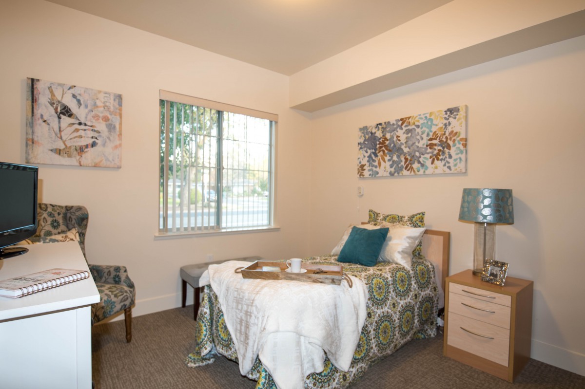 A cozy bedroom with a single bed, decorative pillows, and artwork on the walls.