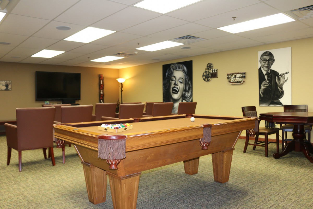 A cozy recreation room featuring a pool table, comfortable seating, and artwork on the walls.