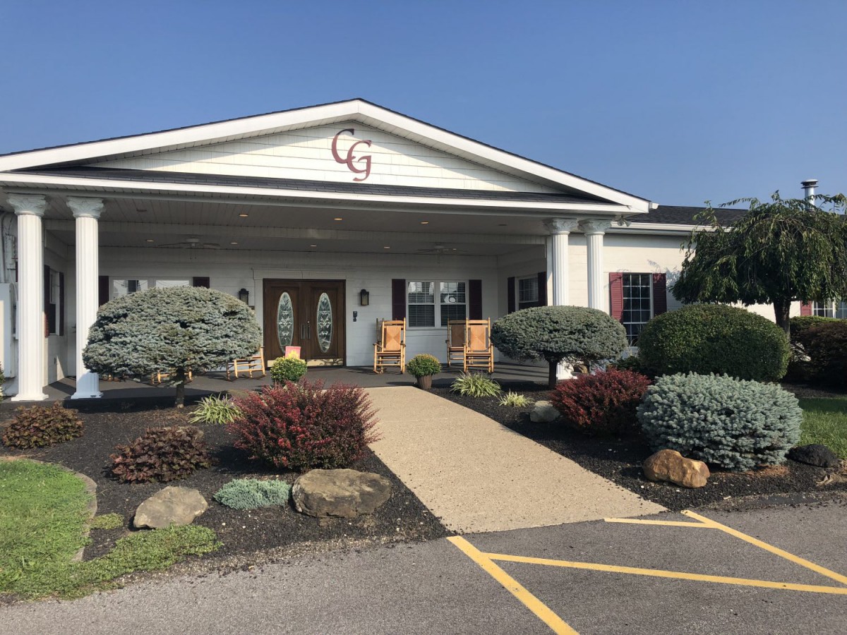 A well-maintained building entrance with a landscaped garden and a paved pathway leading to the doors.