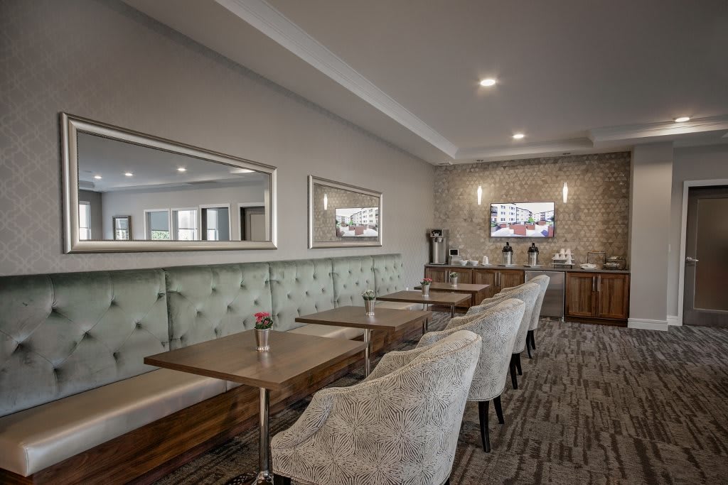 A modern lounge area with comfortable seating, mirrors on the wall, and a coffee station in the background.