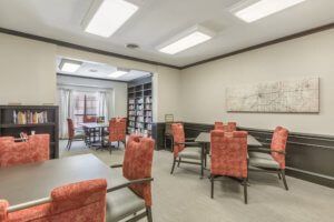 A well-lit meeting room with red upholstered chairs around tables.