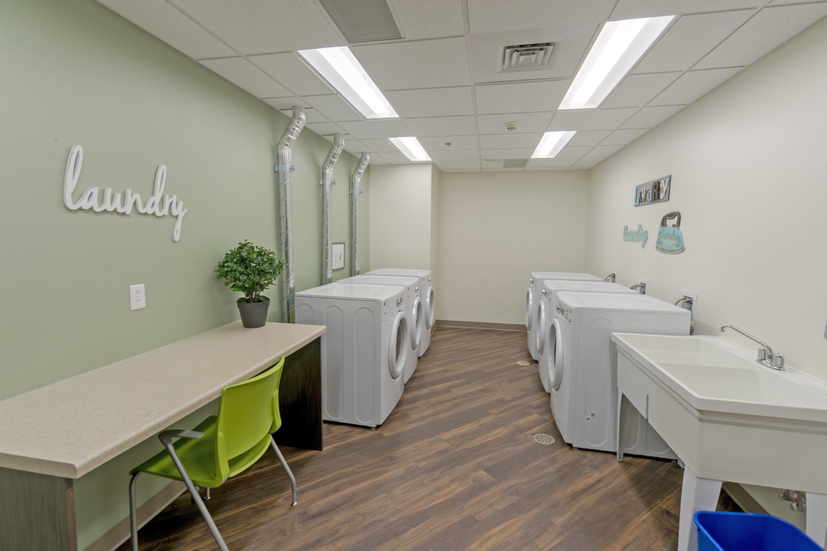 A modern laundry room with washing machines, dryers, and a folding area.