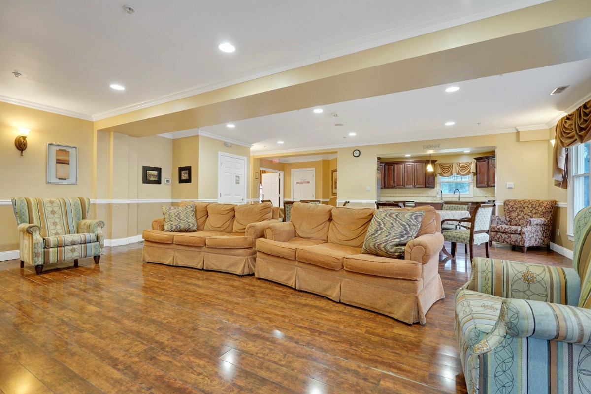 Spacious living room with cozy sofas and hardwood flooring leading into an open kitchen area.