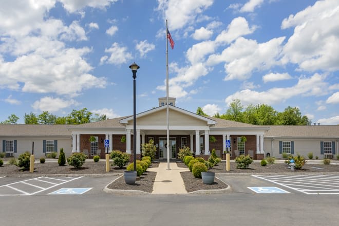 A community center building with a flagpole in the front, surrounded by neatly landscaped greenery.