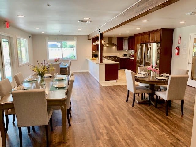 A modern open-concept kitchen and dining area with wood flooring and elegant furniture.