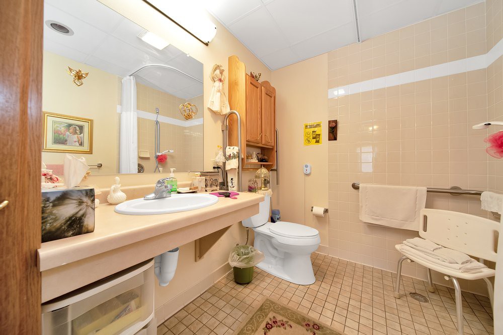 A clean and well-organized bathroom featuring a sink, mirror, toilet, cabinet, and tiled flooring.