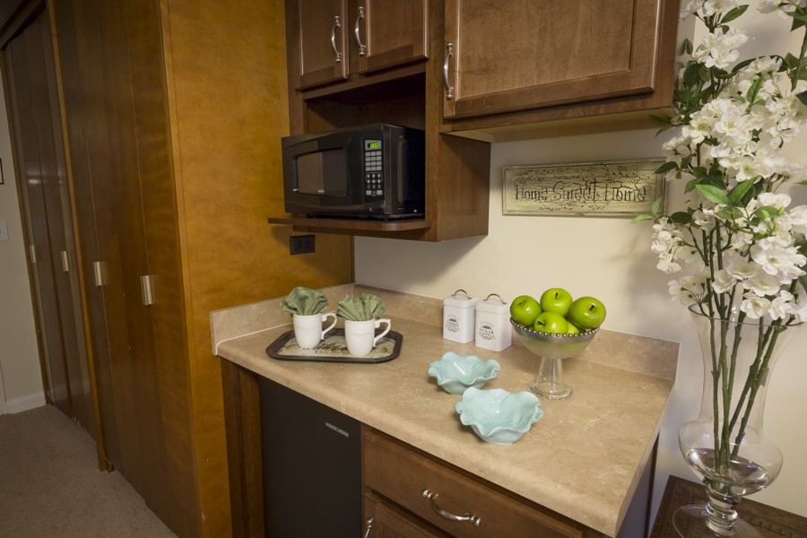A cozy kitchen corner with wooden cabinets, a microwave, and decorative items arranged on the countertop.