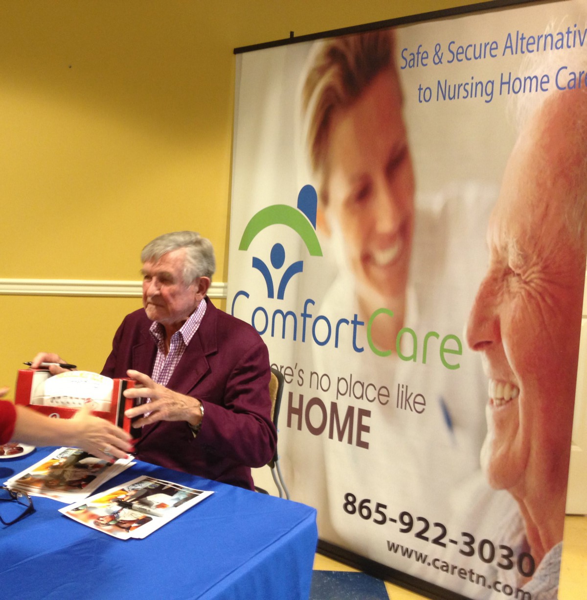 A person attending a book signing event at a Comfort Care promotional booth.