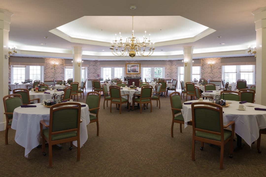 An elegant dining room with neatly arranged tables and a chandelier.