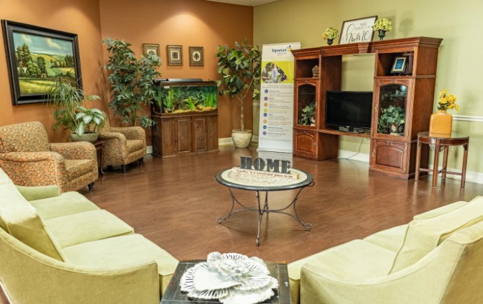 A cozy living room with comfortable seating, a television, plants, and an aquarium.