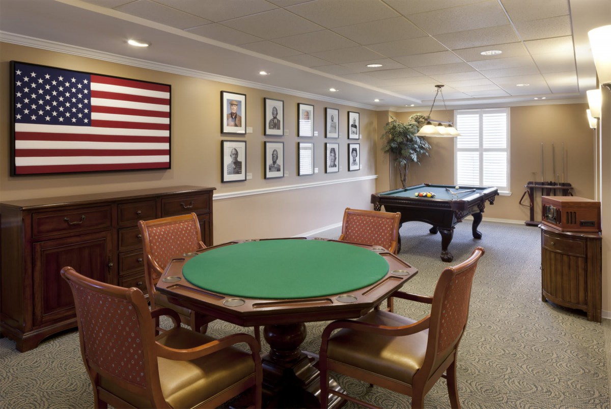 A well-appointed game room featuring a poker table and billiard table, adorned with framed pictures and an American flag.