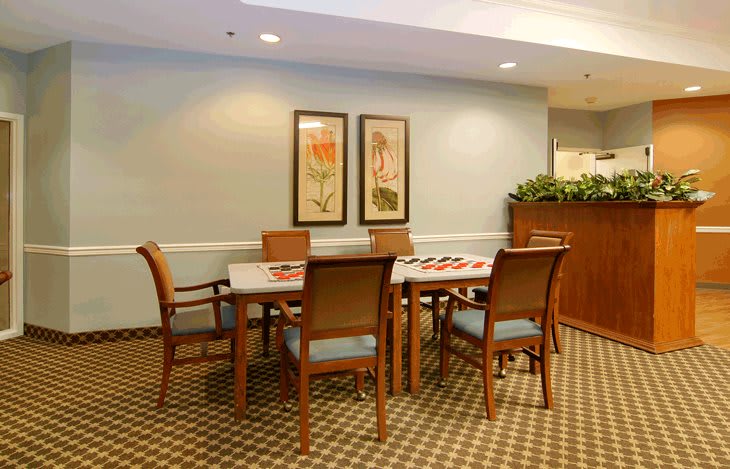 A cozy dining area with a table surrounded by chairs, decorated with artwork and plants.