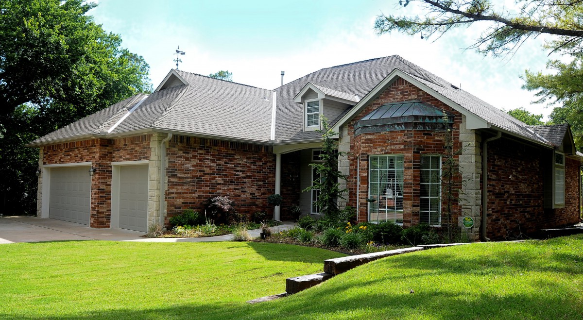 A suburban brick house with a well-maintained lawn and landscaping.