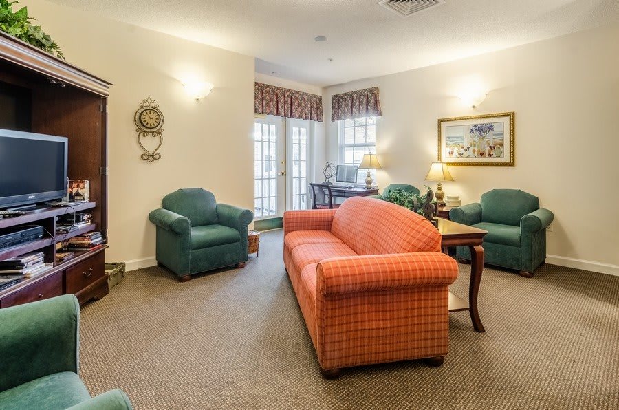 A cozy living room with an orange sofa, green armchairs, and tasteful decor.