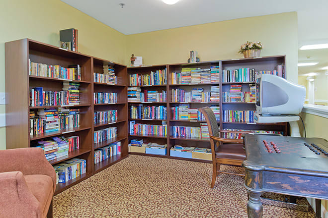 A cozy library with bookshelves, a reading chair, and a computer.