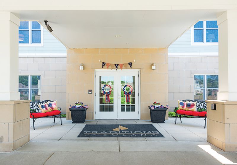 A welcoming entrance with double doors adorned with wreaths and accompanied by benches and planters.