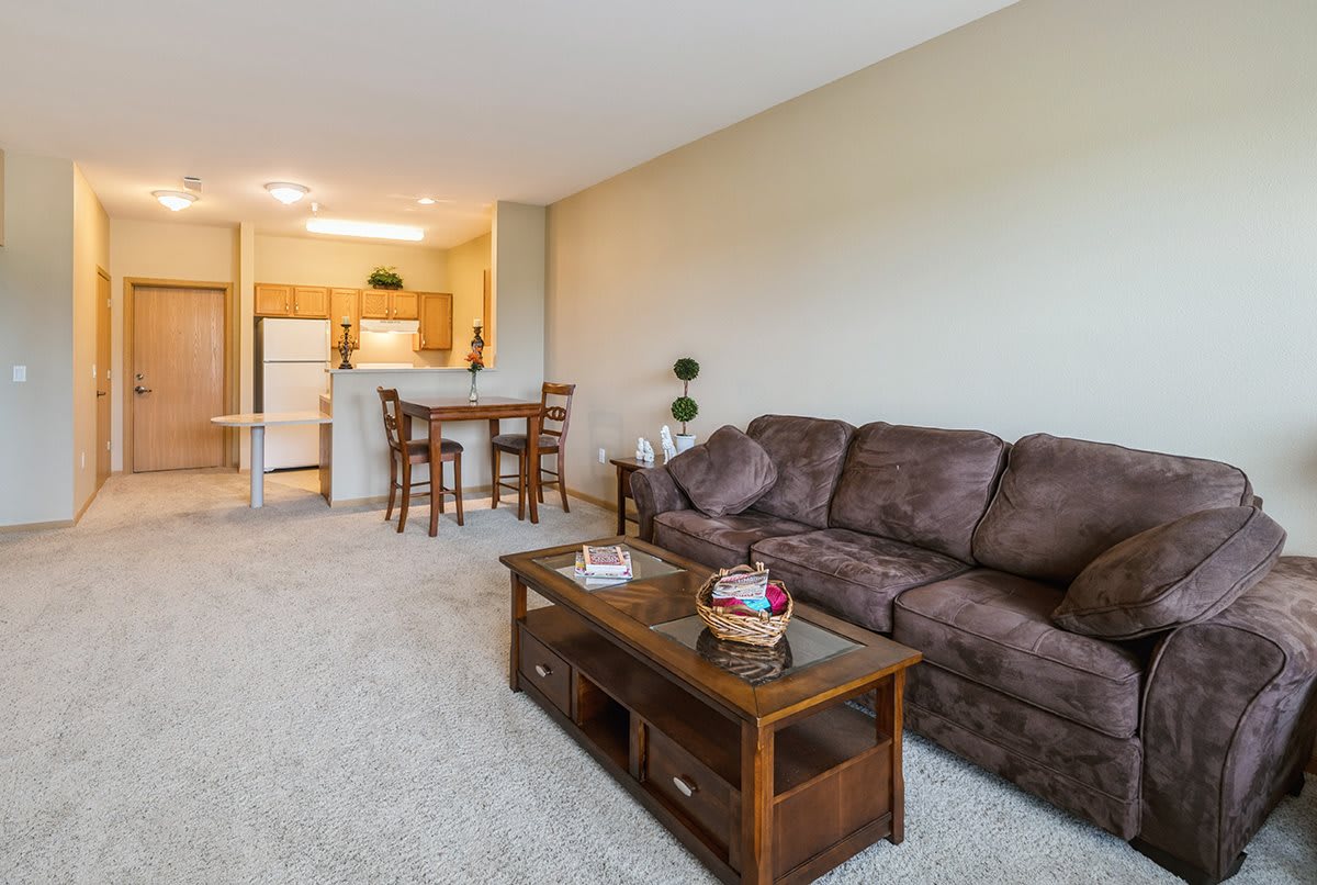 A cozy living room with a sofa and coffee table, leading into a kitchen area with a dining set.