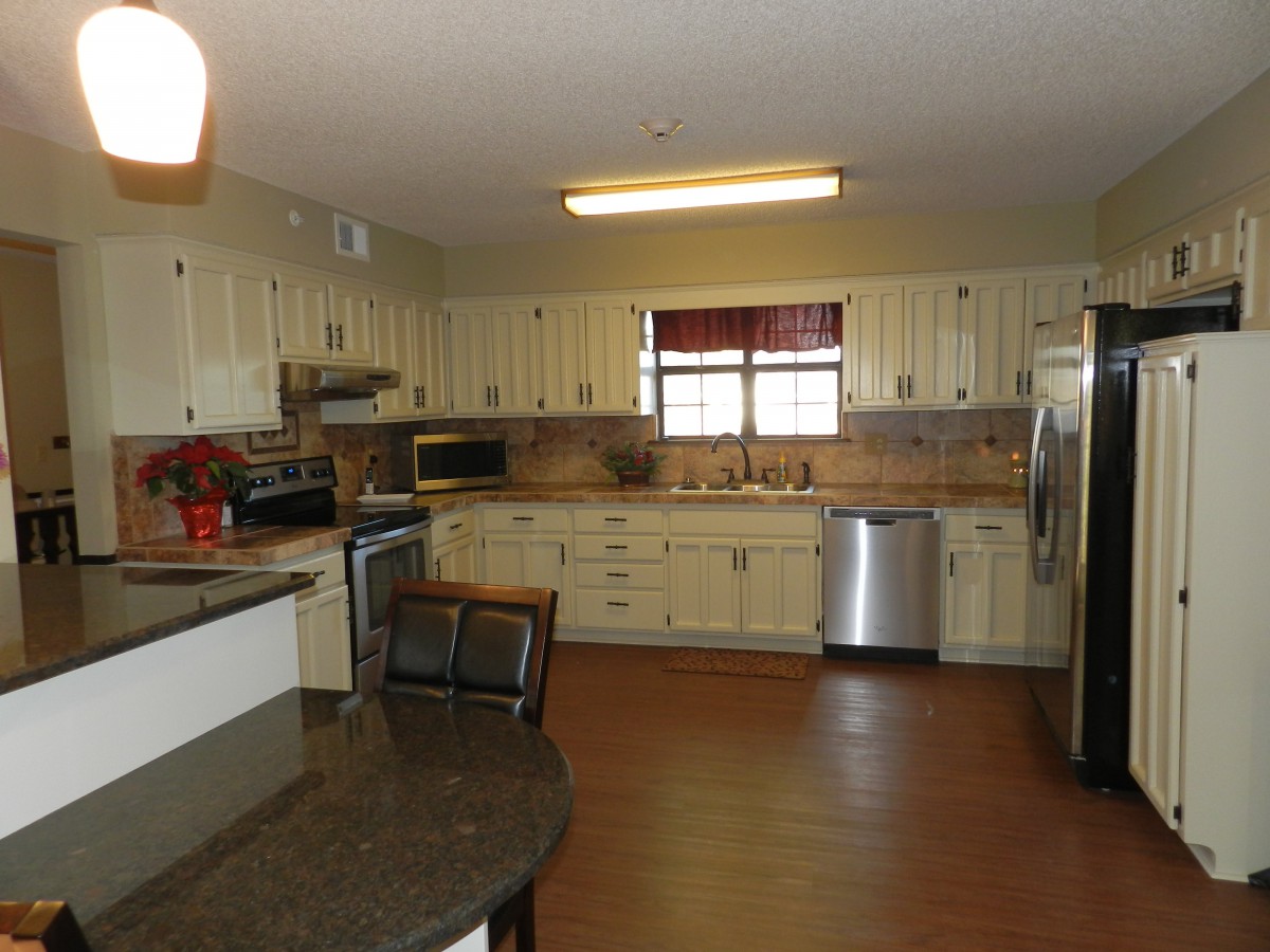 A spacious kitchen with cream-colored cabinets and modern appliances.