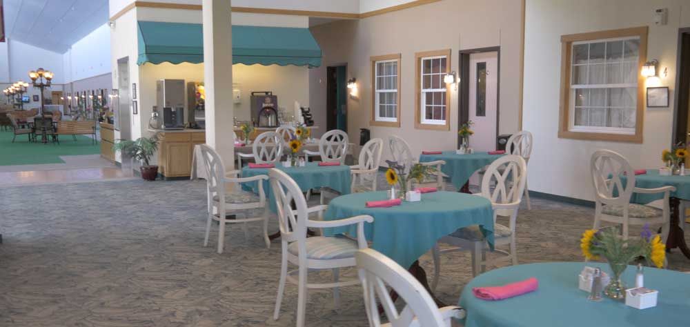 A charming outdoor restaurant patio with tables adorned with teal tablecloths and sunflowers.