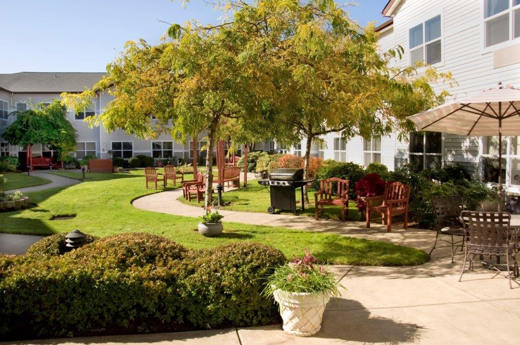 A well-maintained garden courtyard with trees, benches, and a winding pathway.