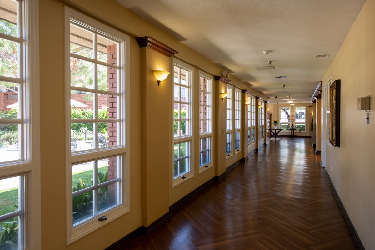 A well-lit hallway with large windows and a wooden floor.
