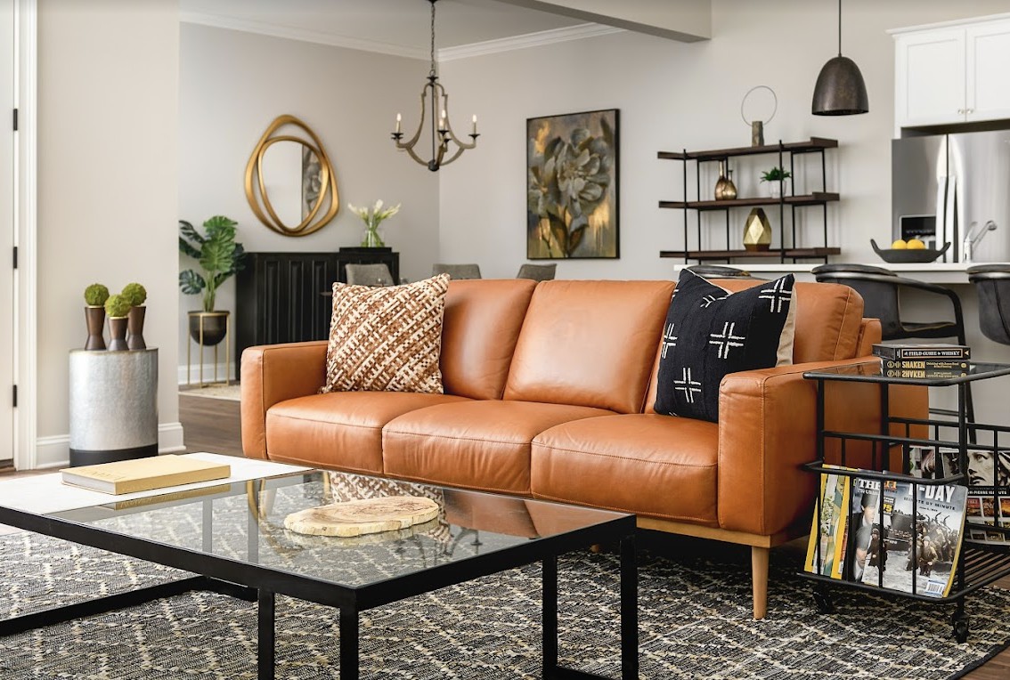 A modern living room featuring a brown leather sofa, stylish decor, and a chic coffee table.